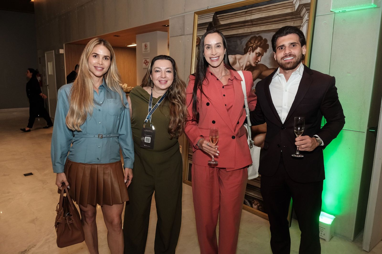Participantes brindando diante de um painel de Michelangelo